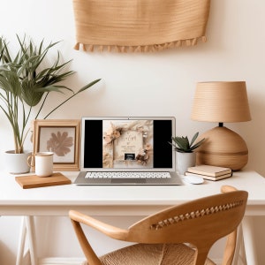 May include: A laptop computer displaying a photo of a wooden sign with the text "It's a Girl!" surrounded by dried flowers and a sonogram image. The laptop is on a white desk with a wooden chair, a lamp, and a framed picture.