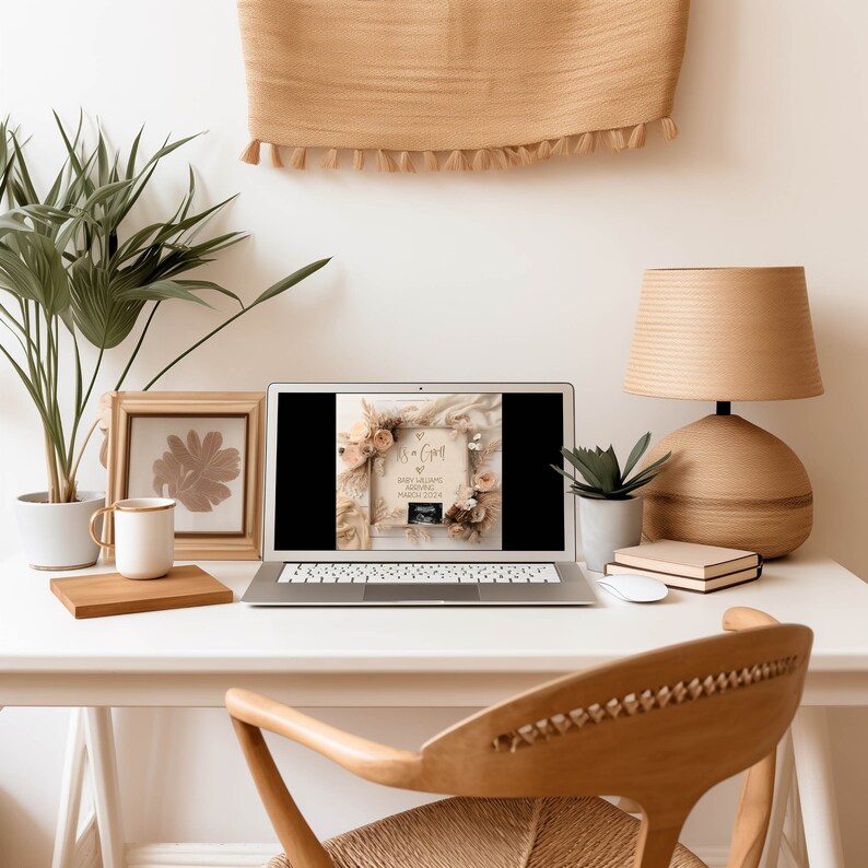 May include: A laptop computer displaying a photo of a wooden sign with the text "It's a Girl!" surrounded by dried flowers and a sonogram image. The laptop is on a white desk with a wooden chair, a lamp, and a framed picture.