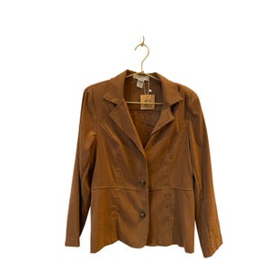 May include: A brown blazer with a notched collar, long sleeves, and two decorative buttons. The blazer is hanging on a gold-colored hanger against a white background. The blazer has a tailored fit and appears to be made of a soft fabric.