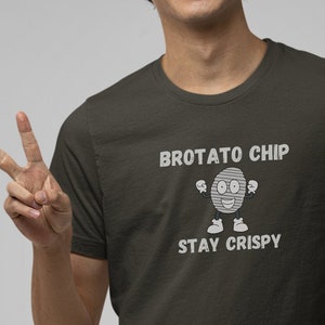 May include: A dark green t-shirt with a white graphic of a potato chip with a face and the text "BROTATO CHIP STAY CRISPY".