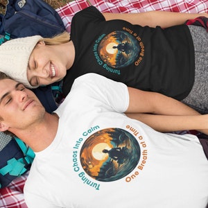 May include: Two people are lying on a red and white checkered blanket. They are wearing white and black t-shirts with a graphic design of a sunset and the text "Turning Chaos Into Calm One Breath at a Time".