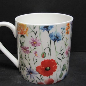 May include: White ceramic mug with a floral pattern featuring red poppies, blue cornflowers, and other colourful wildflowers.