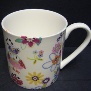 May include: White ceramic mug featuring a colourful floral and owl design. The mug has a large handle and is ideal for hot drinks.