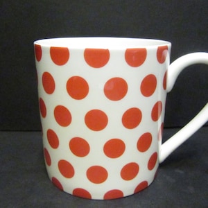 May include: A white ceramic mug with a red polka dot pattern.