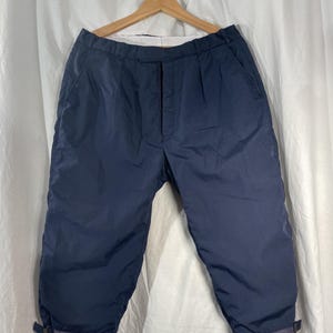 May include: A pair of dark blue, cropped pants with a button fly and a cuffed hem.