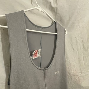 May include: A gray sleeveless zip-up vest with the word "ODLO" printed on the front. A white tag with the words "Sports Life" is attached to the vest.