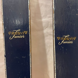 Puede incluir: Par de esquís de madera azul vintage con letras doradas que dicen "GRESVIG Junior".