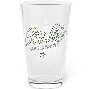 Può includere: Un bicchiere di pinta in vetro trasparente con un design bianco che dice "Blau Kia ORIGINAL" con stelle intorno al testo.