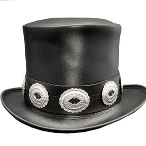 May include: A black top hat with a wide brim and a decorative band. The band features three silver-colored, oval-shaped embellishments. The hat is made of a smooth, possibly leather-like material.