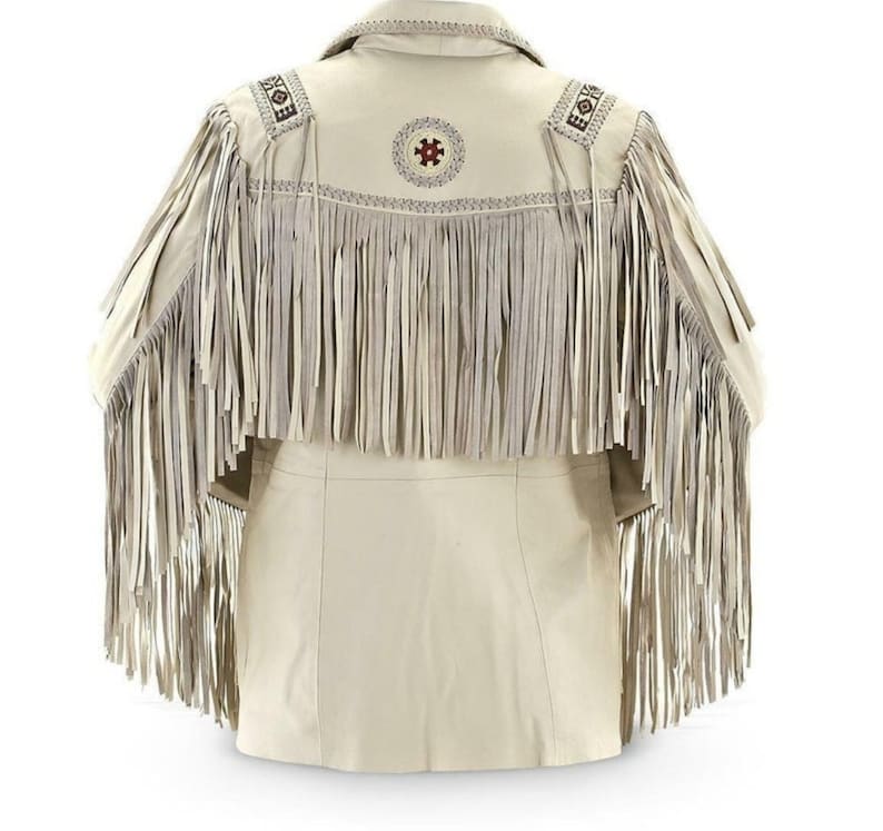May include: Cream leather jacket with long fringe detailing on the back and sleeves. The jacket has decorative stitching and a circular design with red accents on the upper back. A classic western-inspired garment.
