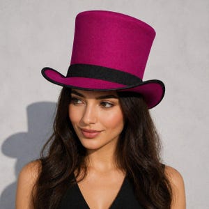 Könnte beinhalten: Ein magenta Zylinderhut mit schwarzem Band und Krempenbesatz. Der Hut hat eine hohe, zylindrische Krone und einen breiten, leicht gebogenen Rand. Der Hut ist aus einem filzartigen Material.