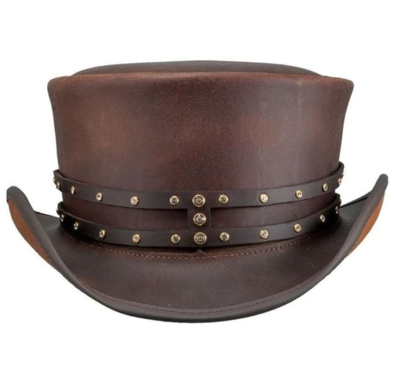 May include: A brown leather top hat with a wide brim. The hat features two dark brown leather bands around the crown, adorned with small, gold-colored rivets. The hat's design is reminiscent of steampunk or Victorian styles.