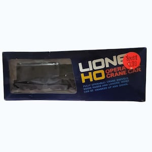 May include: A boxed Lionel HO Opera Crane Car. The dark blue box features the Lionel logo and product details in white and yellow. The crane car is visible through a clear plastic window. The text reads: "FULLY OPERABLE! CRANE SWIVELS. BOOM RAISES AND LOWERS, HOIST CAN BE CRANKED UP AND DOWN."