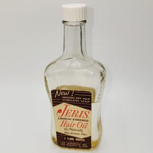 May include: A clear glass Jeris Hair Oil bottle with a white cap. The label reads "Jeris Lanolin-Enriched Hair Oil" and "7 Fluid Ounces". The bottle is designed to groom dry hair and stimulate the scalp.