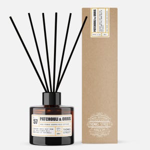 May include: A brown glass reed diffuser with black reeds and a black cap. The label reads "Patchouli & Orris" and "Thomas Street". The packaging is a tall, brown box with the same text. The diffuser contains 100ml of scented oil.
