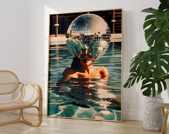 May include: A woman with a disco ball over her head is submerged in a swimming pool. The water is a vibrant turquoise color and the disco ball reflects the light.
