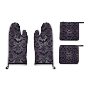 May include: A set of two purple and black oven mitts and two matching pot holders with a bat and damask pattern.