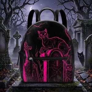 May include: Black backpack featuring a neon pink illustration of a cat on a tombstone in a graveyard setting. The backpack has a zipper closure and black straps. The background shows a spooky graveyard scene with trees and a moon.