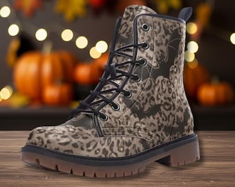 Pode incluir: Uma bota de combate castanha e preta com um padrão de leopardo e silhuetas de morcegos. A bota tem atacadores pretos, sola castanha e um pequeno salto. O fundo apresenta abóboras e folhas de outono.