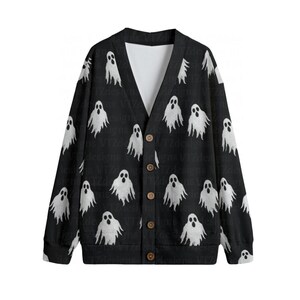 May include: A black long-sleeve V-neck cardigan featuring an all-over white ghost pattern. The garment has a button-down front closure with five brown circular buttons, ribbed cuffs, and a white interior lining visible at the neckline.