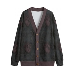 Könnte beinhalten: Eine dunkelgraue Strickjacke mit V-Ausschnitt, verziert mit einem sich wiederholenden anatomischen Herzmuster und feinen Schnörkeldetails. Das Kleidungsstück hat eine dunkelbraune Knopfleiste mit fünf Knöpfen, lange Ärmel und einen weißen Kragen.