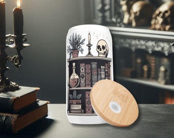 May include: White tumbler with a bamboo lid, featuring a bookshelf design with a skull, candles, and books. The tumbler has a black and white illustration of a shelf with various gothic-themed items.