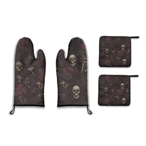 Könnte beinhalten: Ein Set aus Ofenhandschuhen und Topflappen mit dunklem Hintergrund. Das Muster zeigt Totenköpfe, Rosen, Pilze und Spinnweben in Grau-, Burgunder- und Weißtönen. Die Ofenhandschuhe haben schwarze Aufhängeschlaufen.
