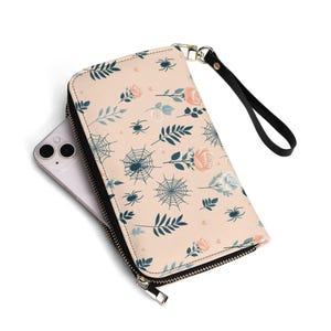 Cartera de piel con diseño de telarañas y rosas, estilo gótico floral con arañas y correa de muñeca extraíble.