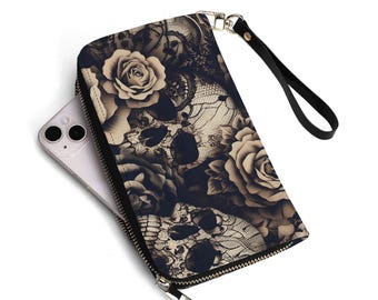 Puede incluir: Una cartera floral negra y beige con un diseño de calavera. La cartera tiene cierre de cremallera, una correa de muñeca negra y un cierre de metal plateado. Un teléfono inteligente es parcialmente visible.