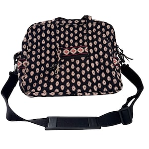 Puede incluir: Bolso de viaje negro con estampado de cachemir blanco y correa de hombro negra. El bolso tiene un bolsillo frontal con cremallera con un detalle estampado en rojo y blanco. También tiene dos bolsillos laterales y dos asas superiores.