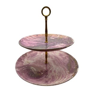 Puede incluir: Bandeja de servir de dos niveles con asa y soporte dorados. Los platos redondos tienen un patrón de remolino morado y blanco. La bandeja está diseñada para servir postres o aperitivos.
