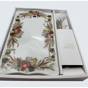 May include: A white rectangular serving platter with a decorative border featuring apples, pinecones, and wheat. The platter is in a white box, with a small knife. The design includes shades of red, brown, and yellow.