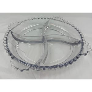 May include: Clear, divided serving dish with four sections. The dish has a beaded edge and curved handles. Ideal for serving snacks, appetizers, or dips. The clear design allows the contents to be visible.