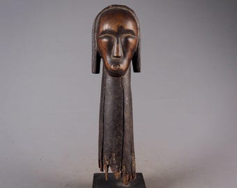 May include: A wooden sculpture of a human head with a long neck. The sculpture is dark brown and has a simple, stylized face.