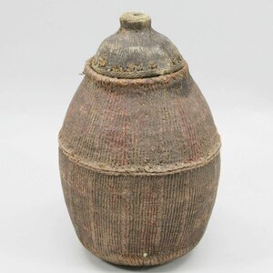 May include: A brown woven basket with a lid made of wood. The basket is oval shaped and has a rough texture.