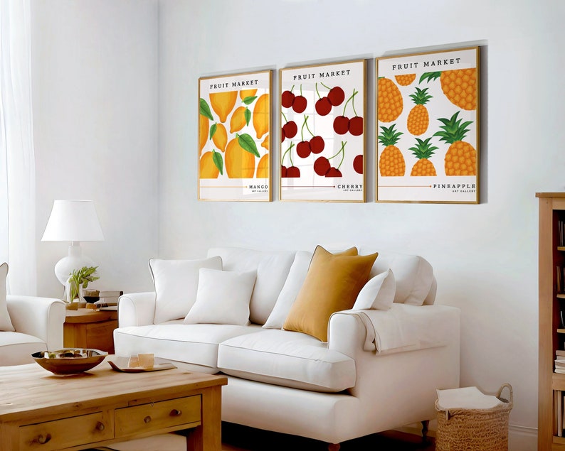 May include: Three framed prints with a white background and a gold frame. Each print features a different fruit: mango, cherry, and pineapple. The text "Fruit Market" is at the top of each print.