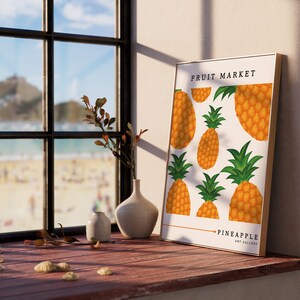 May include: A framed print with a white background and a pattern of yellow pineapples. The print has the text "Fruit Market" and "Pineapple Art Gallery" at the top and bottom.