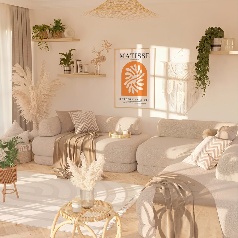 Puede incluir: Una sala de estar con un sof&aacute; seccional beige, una alfombra blanca y una mesa auxiliar con un jarr&oacute;n de hierba de pampa seca. La pared detr&aacute;s del sof&aacute; presenta una impresi&oacute;n enmarcada de un dise&ntilde;o abstracto naranja y blanco con el texto "MATISSE" y "BERGGRUEN & CIE".
