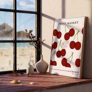 May include: A framed print with a white background and red cherries. The print says "Fruit Market" and "Cherry Art Gallery".