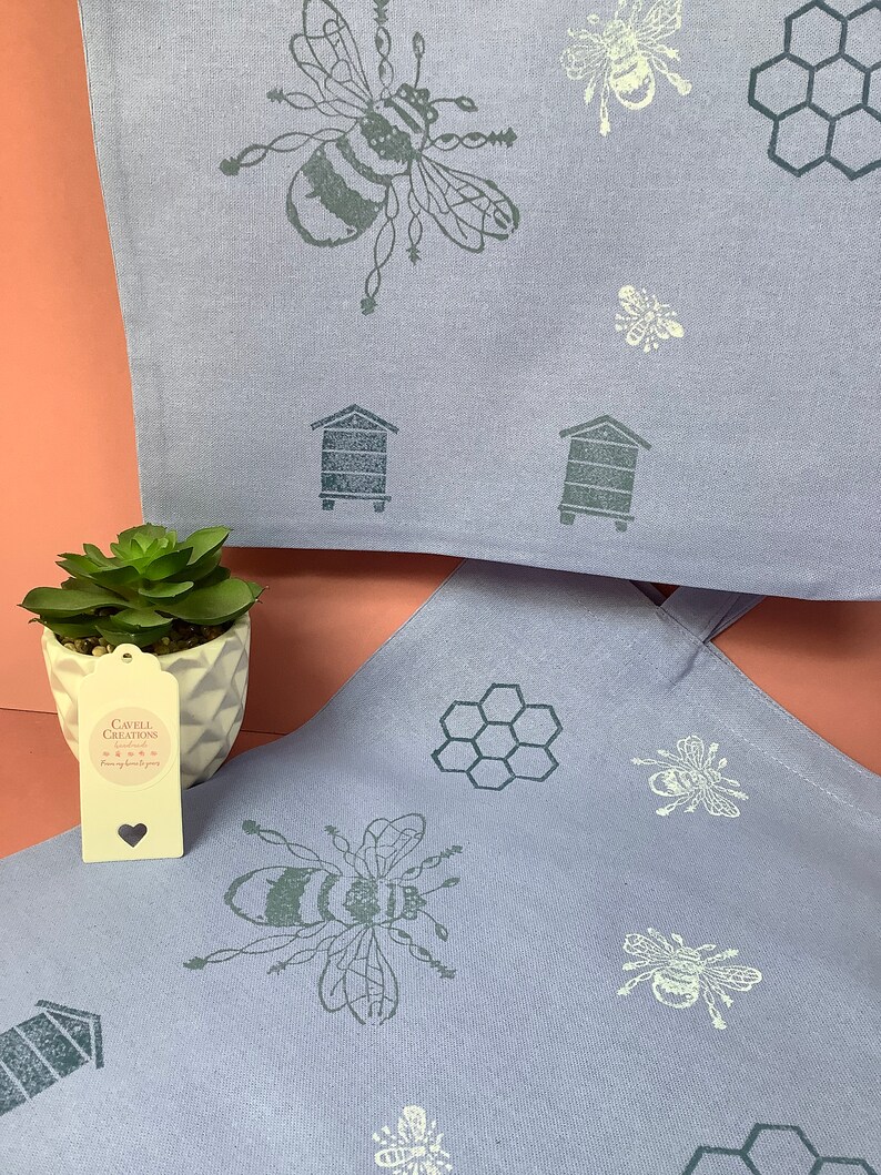 Puede incluir: Dos bolsas de tela lavanda con un dise&ntilde;o de abeja y panal. Las bolsas tienen una abeja en blanco y negro, un panal y un dise&ntilde;o de colmena. Las bolsas est&aacute;n hechas de una tela suave y natural. Las bolsas son perfectas para llevar comestibles, libros u otros art&iacute;culos.