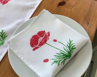 Handprinted cotton table napkin with red poppy and bee design.