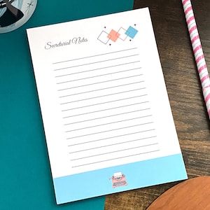 May include: A notepad with the words "Secretarial Notes" in script, featuring a light blue border with a typewriter illustration. The notepad has a retro design with geometric shapes in coral and blue. A pink and white striped pen rests nearby.