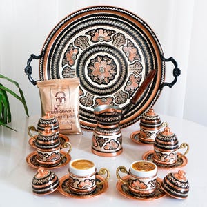 Könnte beinhalten: Ein traditionelles türkisches Kaffee-Set mit einem Kupfertablett, sechs Tassen, einer Kaffeekanne und einer Tüte Kaffee. Das Set ist mit aufwendigen Blumenmustern und schwarzen Akzenten verziert.