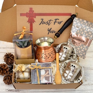 May include: A brown cardboard gift box filled with a variety of items, including a copper Turkish coffee pot, two silver coffee cups, a small potted succulent, a box of Turkish coffee, and a small box of matches. The box is decorated with a red ribbon and the words "Just For You".