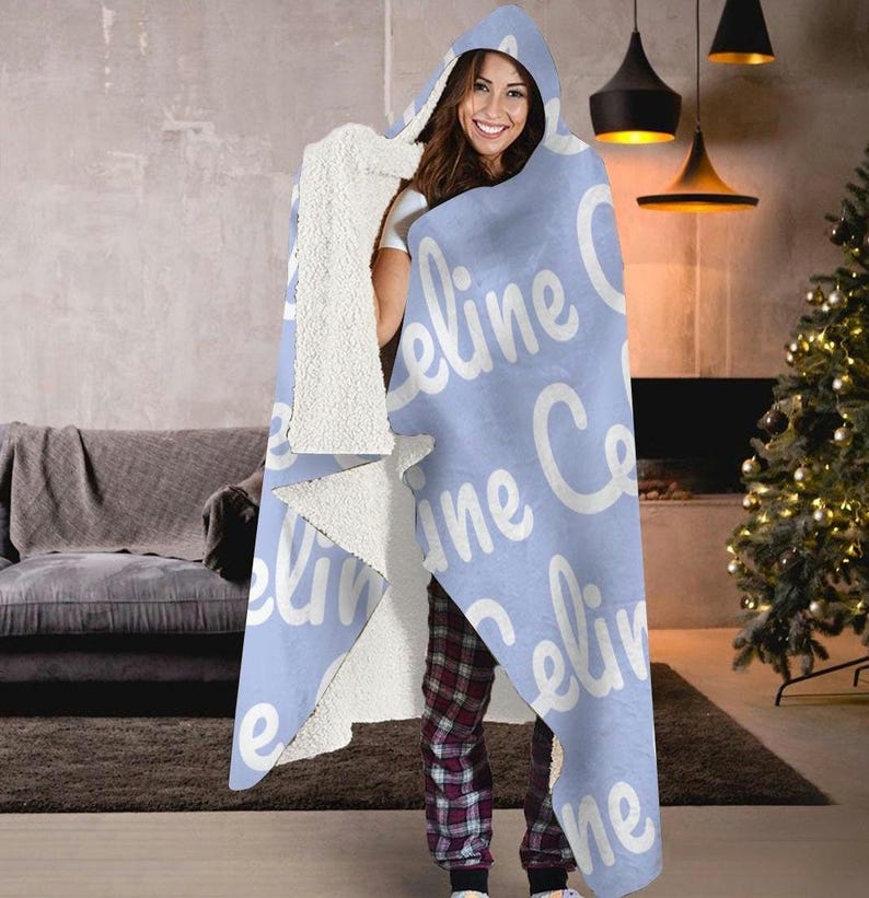 May include: A light blue hooded blanket with the name "Celine" repeated in white text.