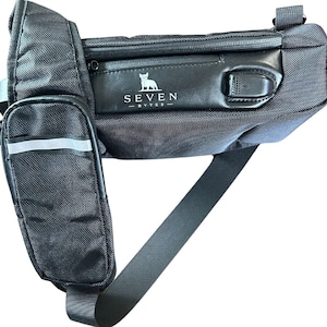 May include: Black crossbody bag with a zipped pocket and a reflective strip on the side. The bag has a strap and a logo that says "SEVEN BYTES" with a dog silhouette.