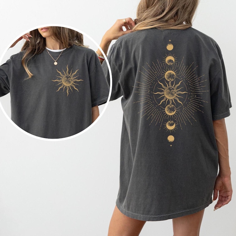 Pu&ograve; includere: T-shirt grigio scuro con grafica dorata del sole sul davanti e un design celeste sul retro. Il design include un sole, le fasi lunari e linee radianti. La maglietta ha maniche corte e una vestibilit&agrave; ampia.