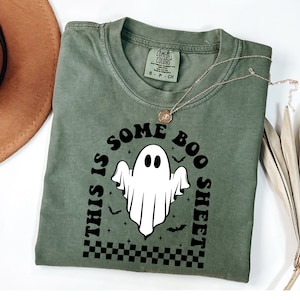 以下が含まれることがあります： 白い幽霊のグラフィックと「This is some boo sheet」というテキストが書かれた緑色のTシャツです。