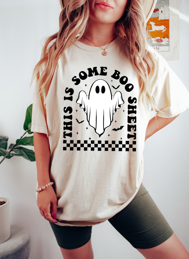 以下が含まれることがあります： 「This is some boo sheet」というテキストと、幽霊の黒いグラフィックが描かれた白いTシャツです。