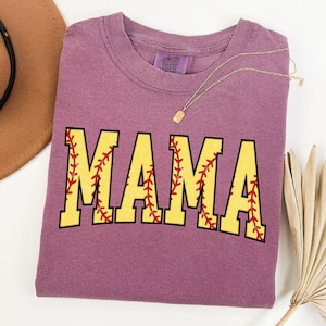 May include: Purple t-shirt with the word "MAMA" in yellow letters with red stitching, resembling a softball.
